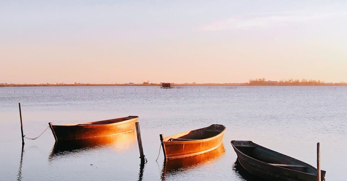 Drei Boote schwimmen bei Sonnenuntergang auf einem See.