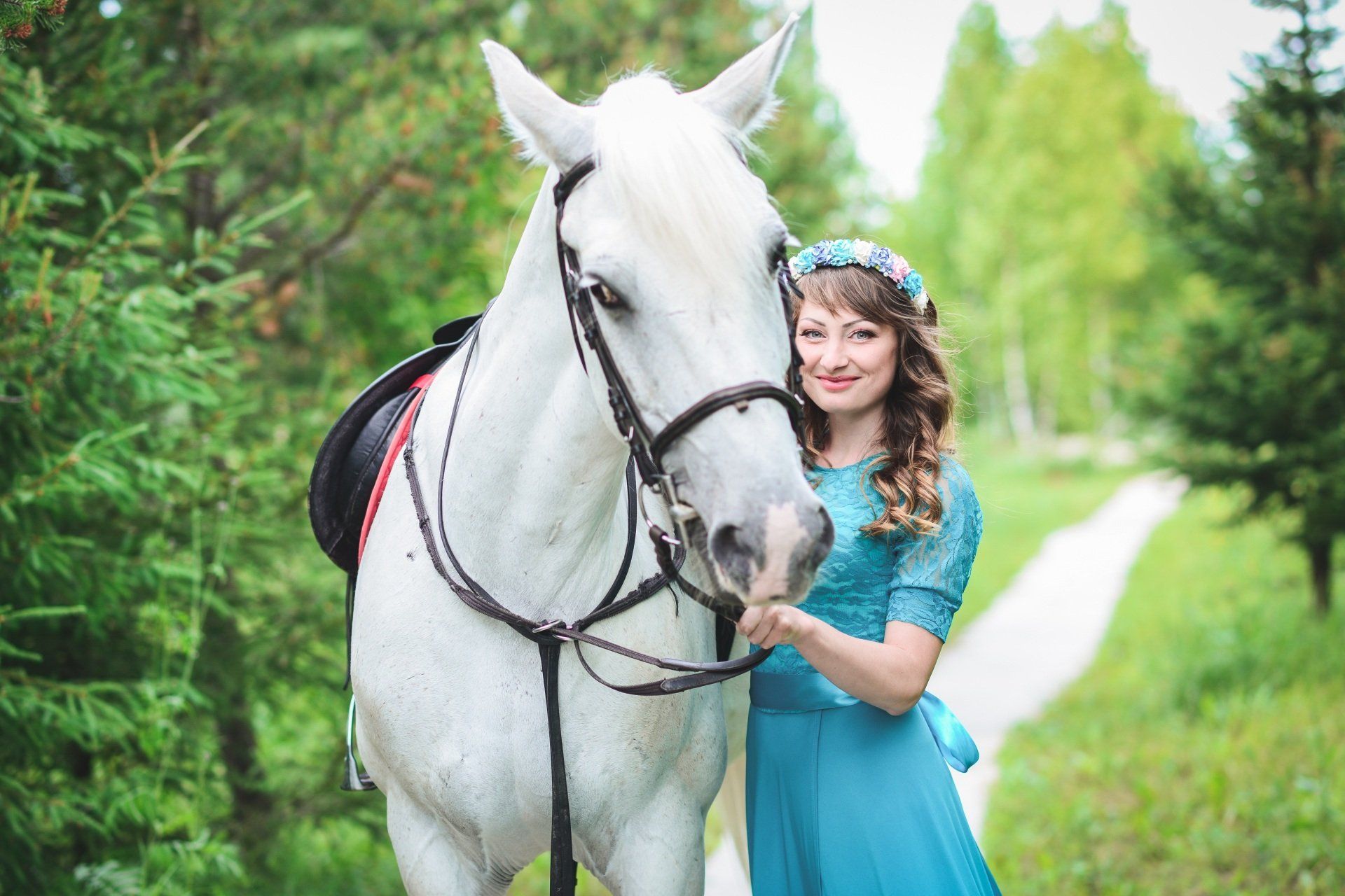 a woman in a blue dress is standing next to a white horse .