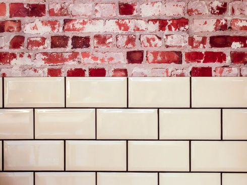 A close up of a brick wall with white tiles on it.