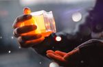A person is holding a jar of honey in their hands.