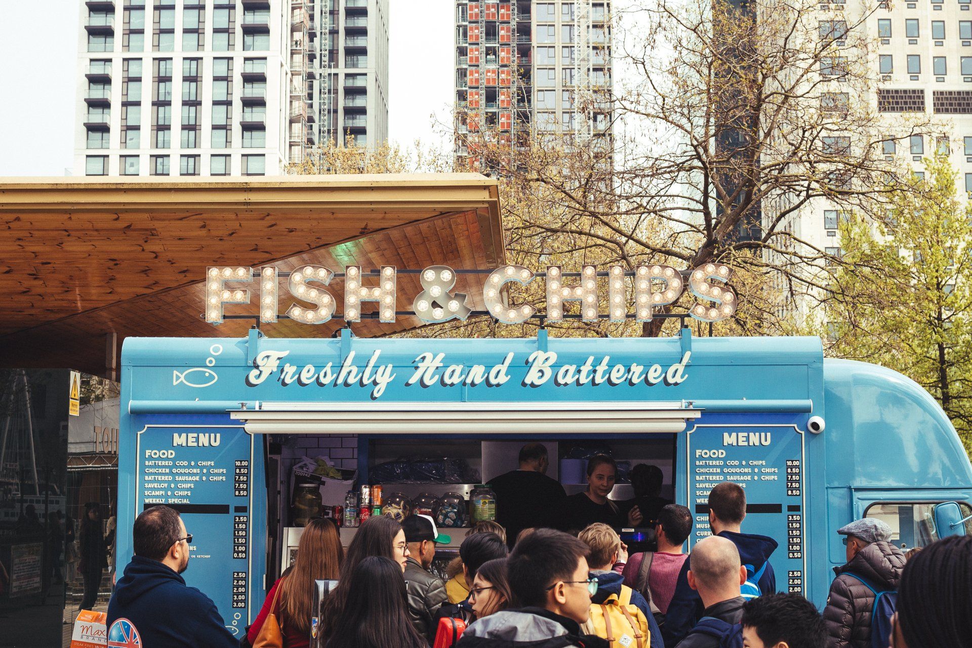 a group of people are standing in front of a fish and chips truck 