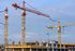 A group of construction cranes are working on a building under construction.