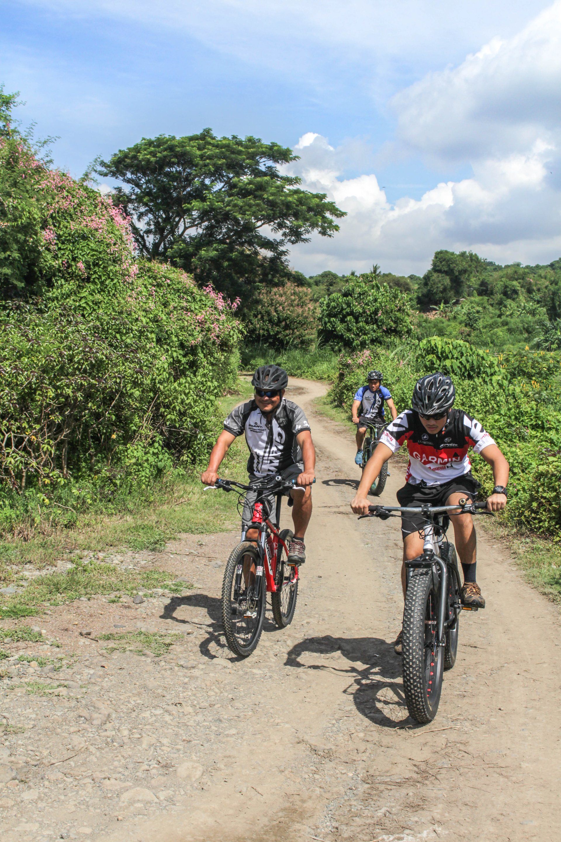 A group of people are riding bicycles down a dirt road.