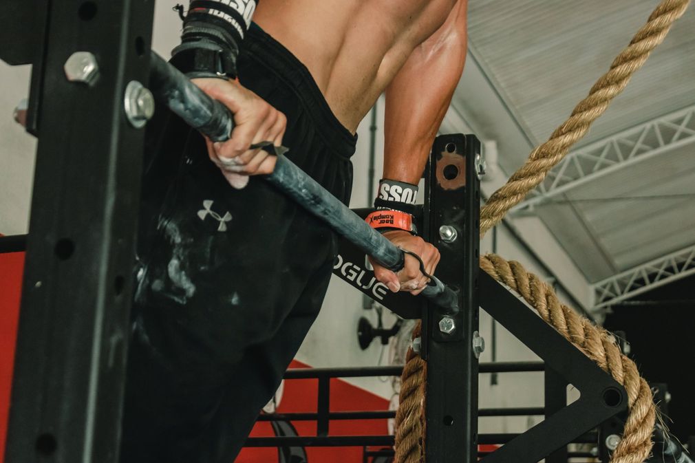 A man is doing a pull up on a bar in a gym.