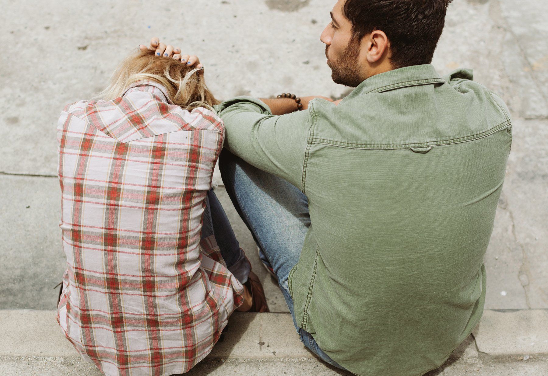 a man in a green shirt sits next to a woman in a plaid shirt after an argument. 