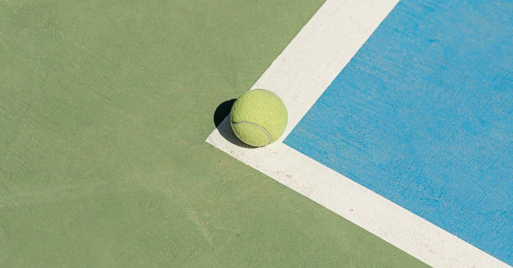 Une balle de tennis est posée sur le coin d'un court de tennis.