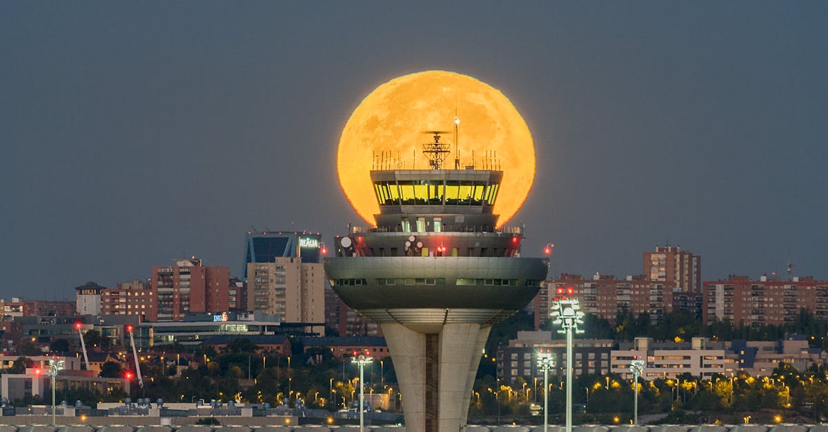 A full moon is rising over an airport control tower