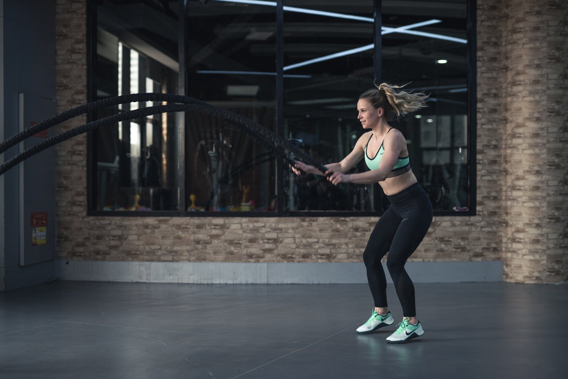 A woman is doing exercises with a rope in a gym.