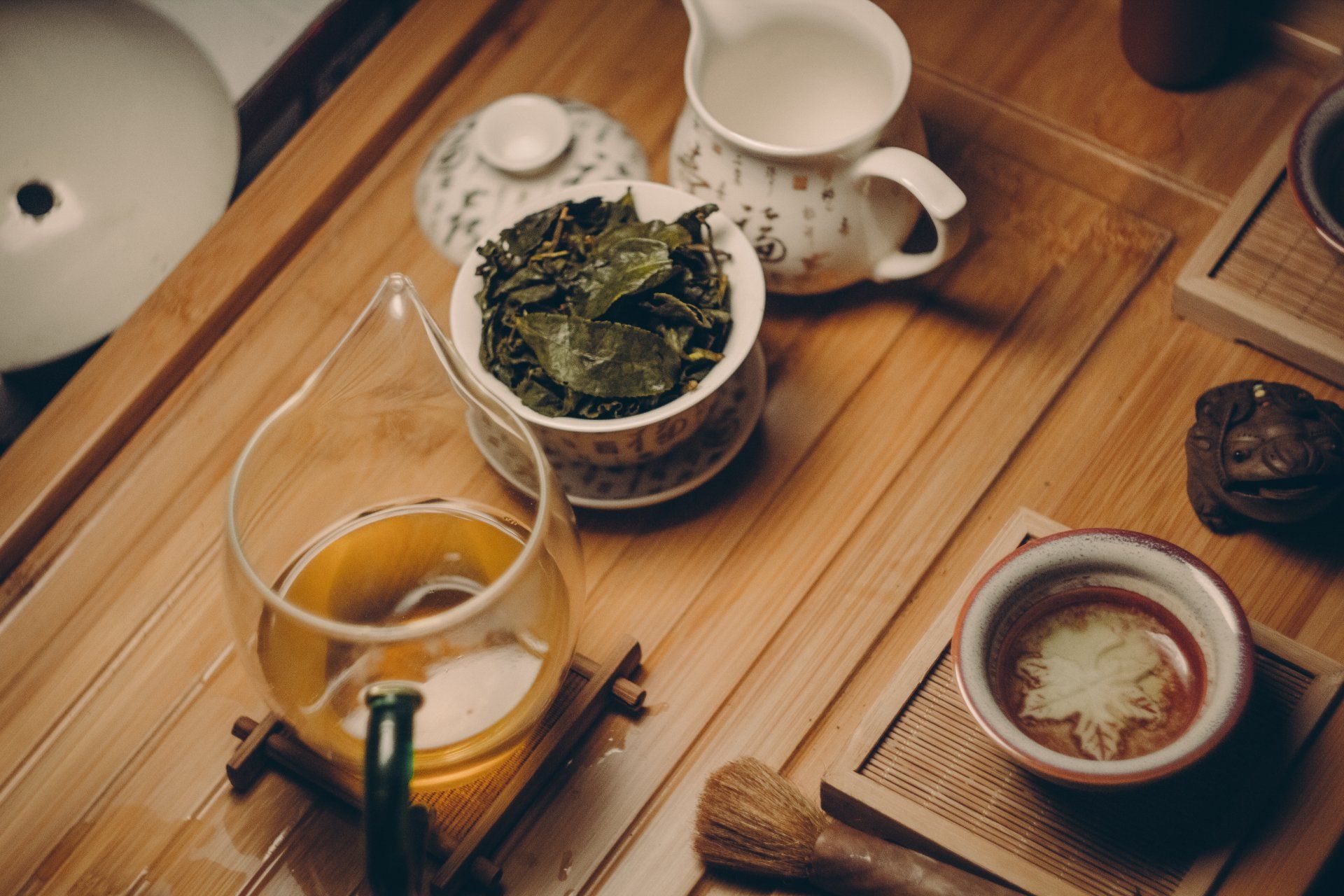 A glass of tea is sitting on a wooden table next to a bowl of tea.