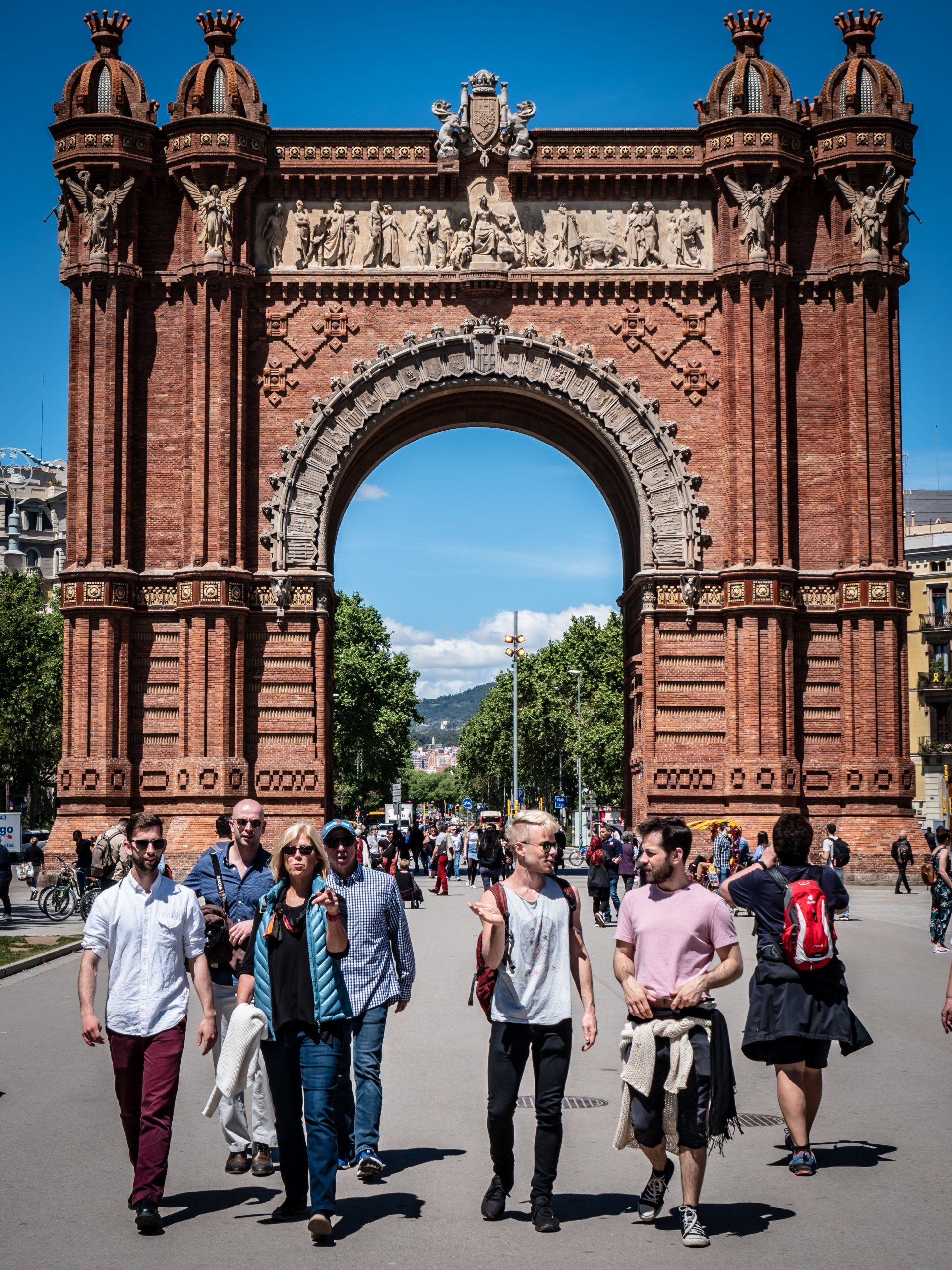 A group of people are walking in front of a large brick archway