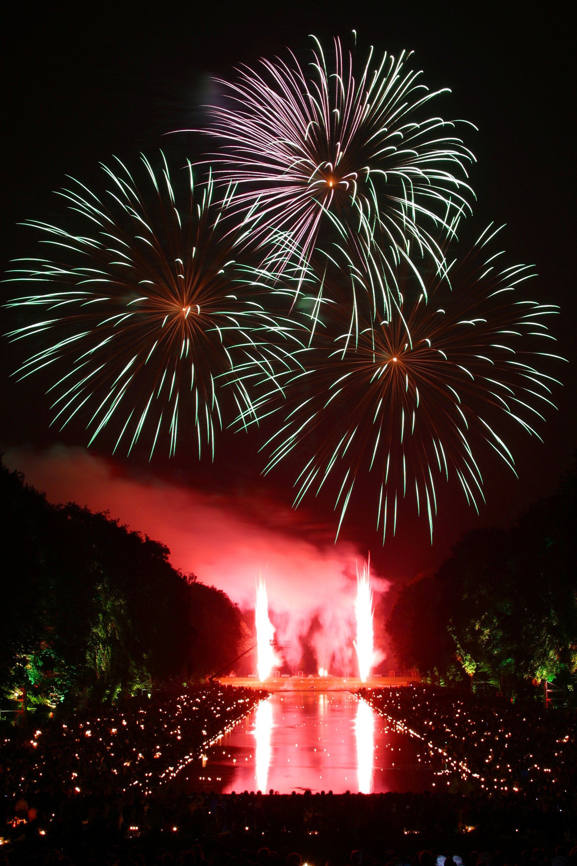 A fireworks display with a fountain in the foreground