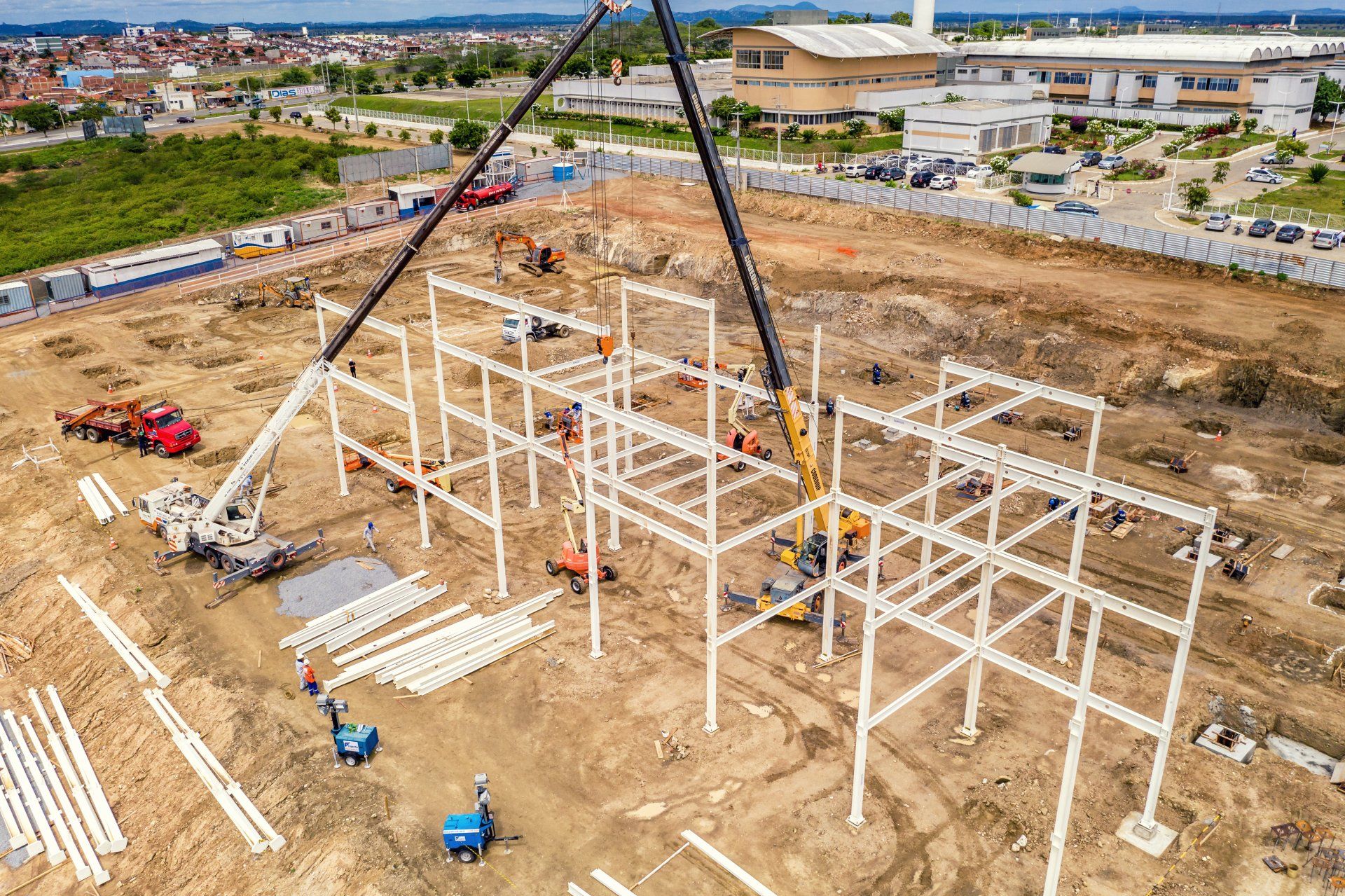 An aerial view of a construction site with a crane lifting a metal structure.