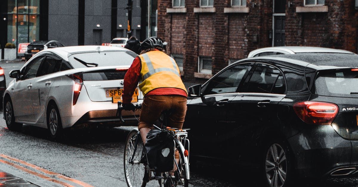 A man is riding a bike on a city street next to a car.