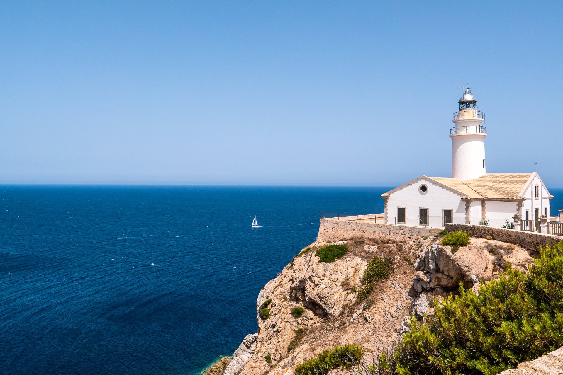 A lighthouse is sitting on top of a cliff overlooking the ocean.