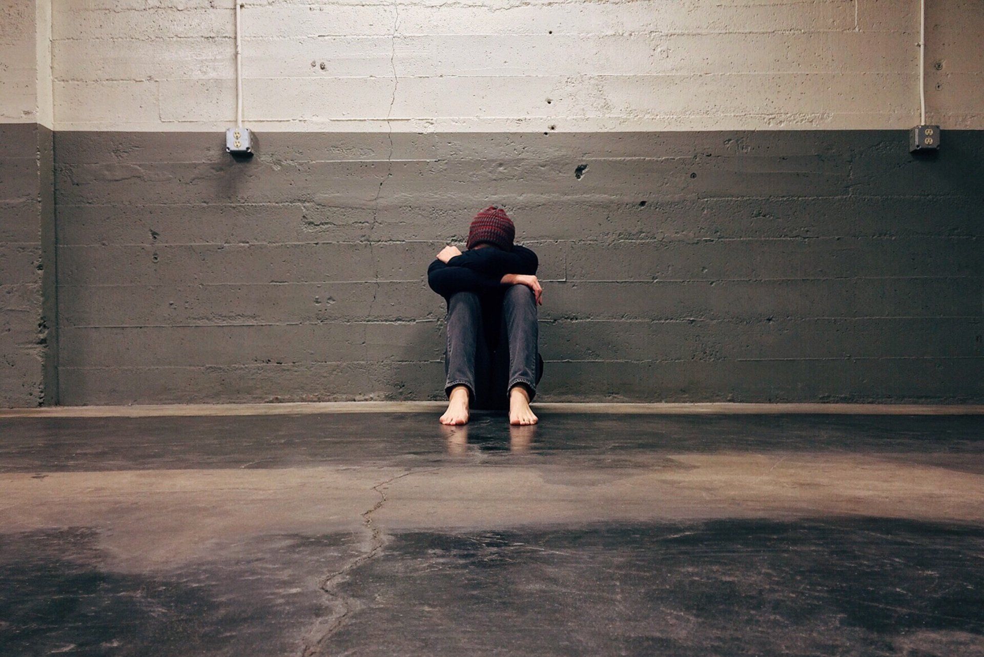 A person is sitting on the floor in a dark room.