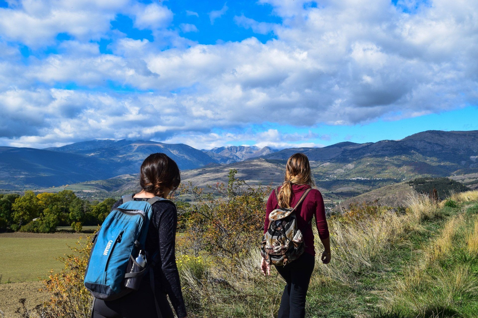 due donne con gli zaini stanno camminando lungo un sentiero in montagna.
