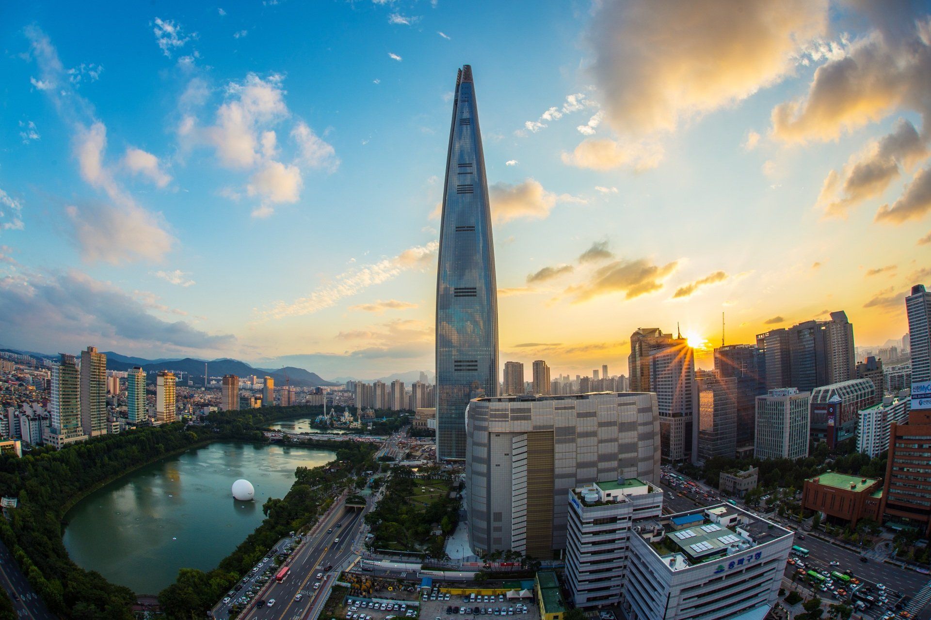 An aerial view of a city skyline at sunset with a very tall building in the foreground.