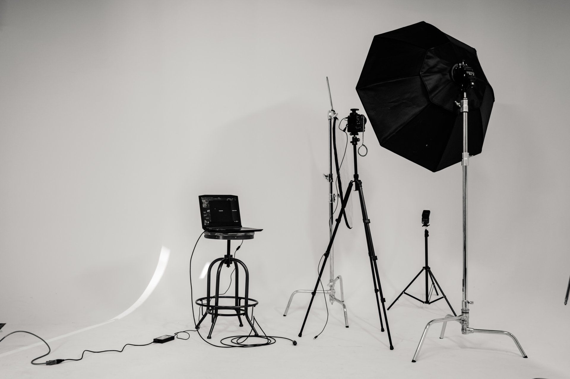 a black and white photo studio with a laptop on a stool