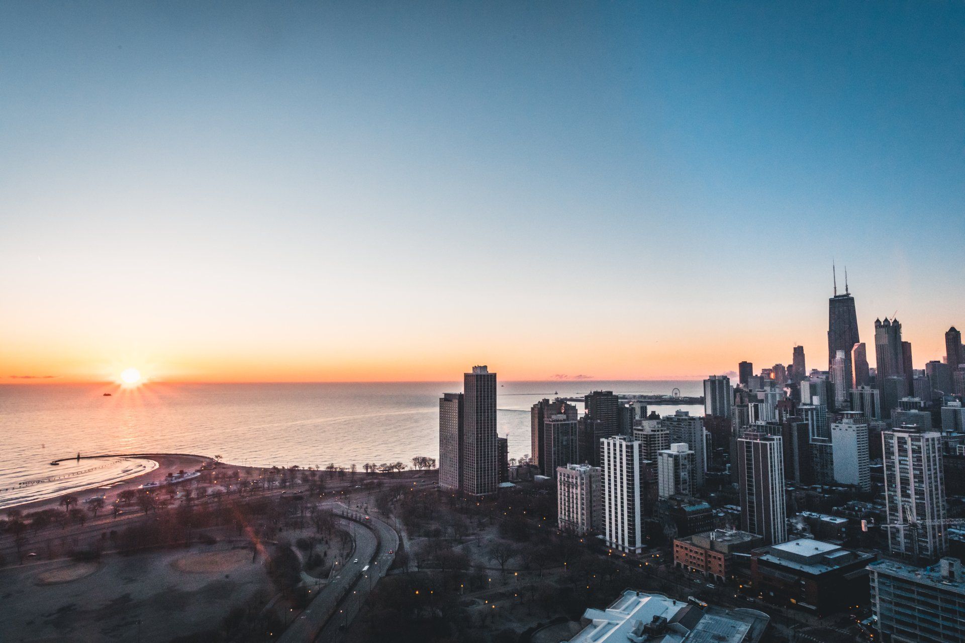 an aerial view of a city skyline at sunset overlooking the ocean .