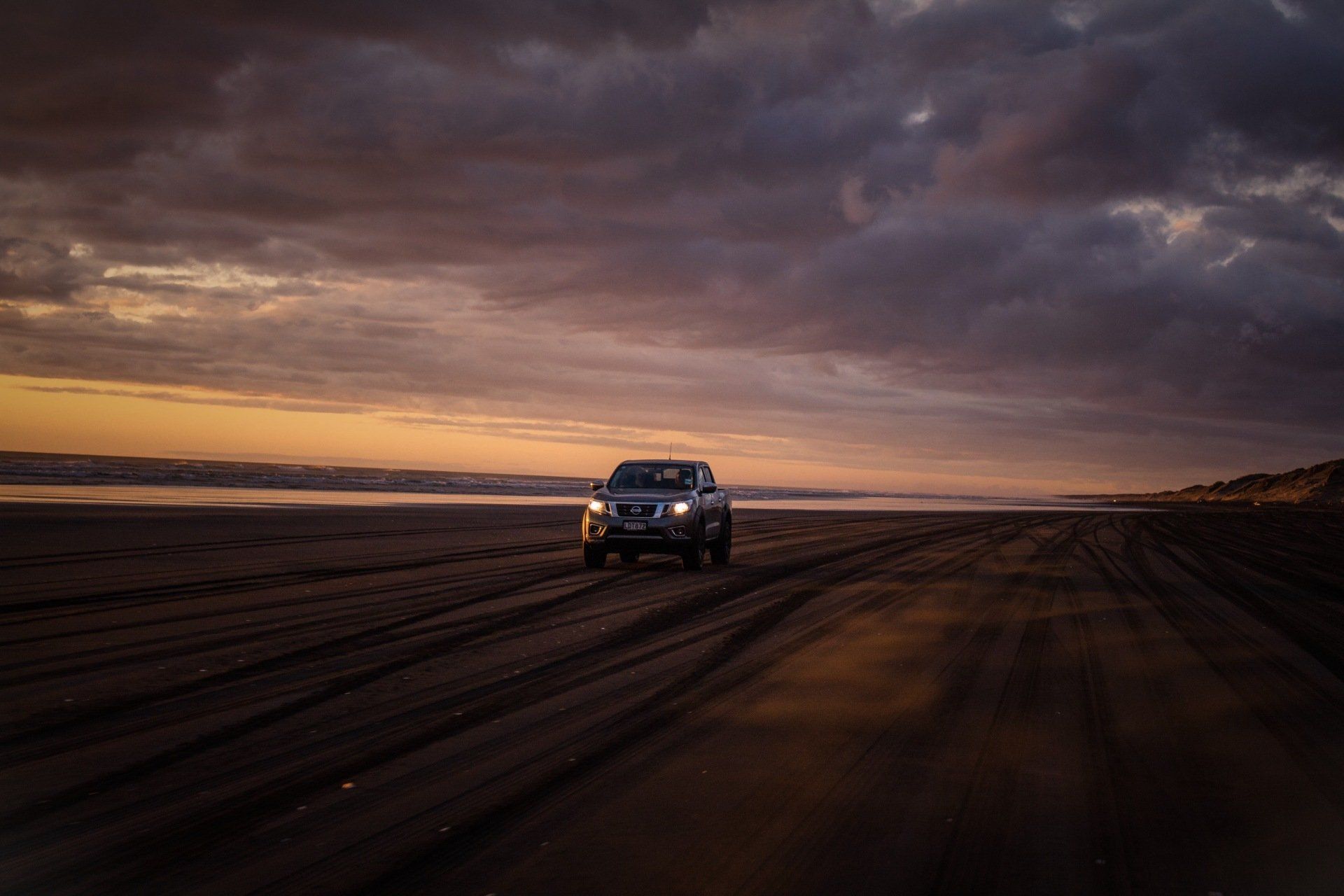 a car is driving on a dirt road near the ocean