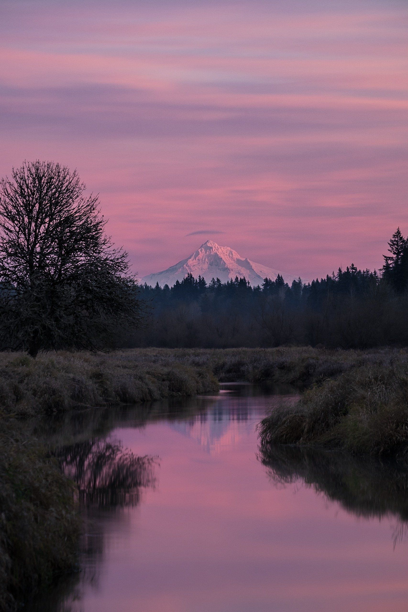 A river with a mountain in the background at sunset.