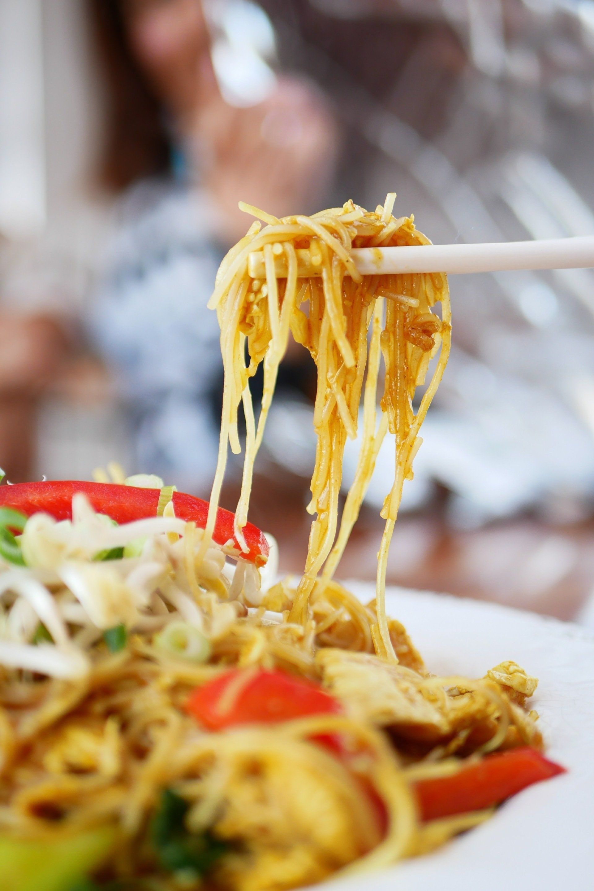 A close up of a person eating noodles with chopsticks
