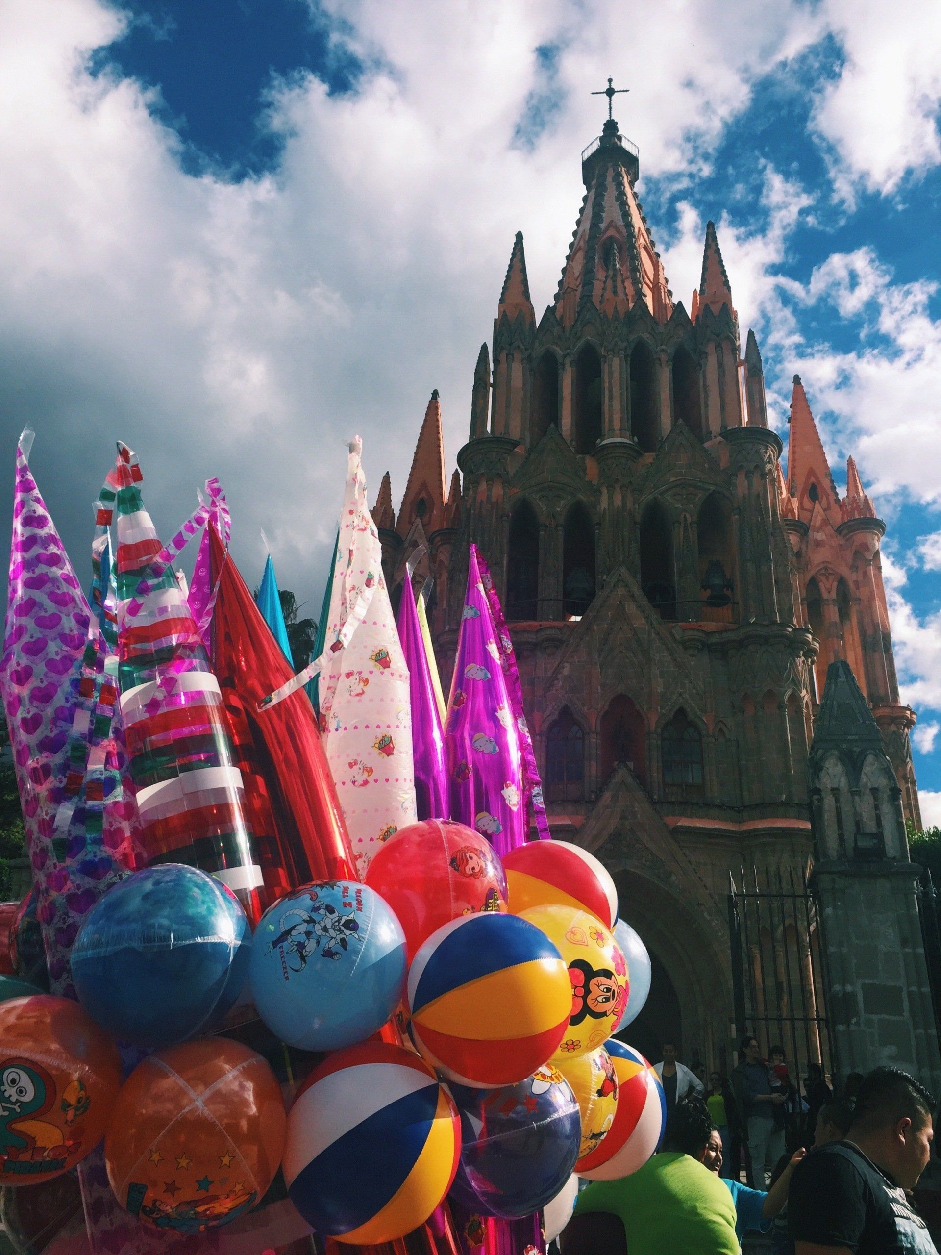 A bunch of balloons and beach balls in front of a church