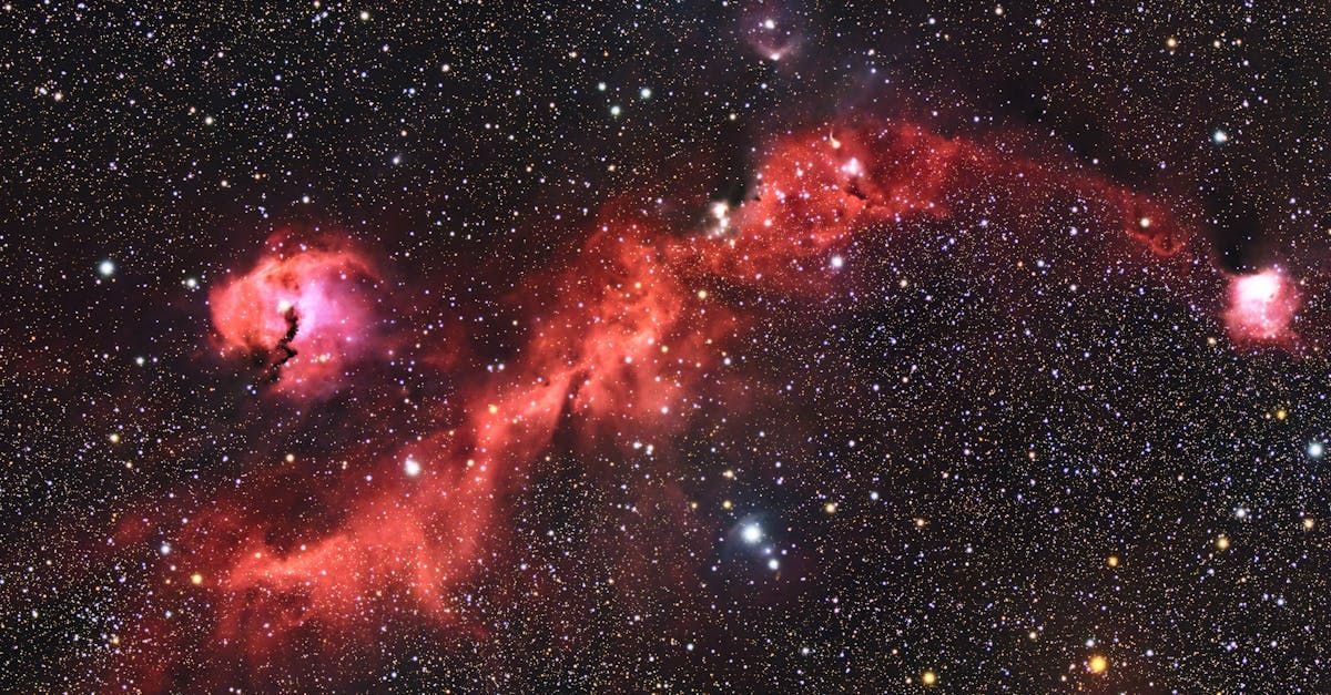 A starry night sky with a red nebula in the middle