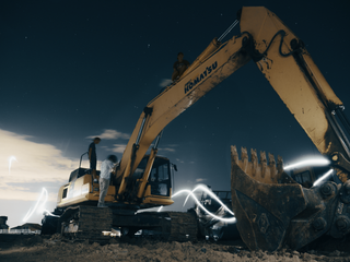 A yellow excavator is working on a construction site at night.