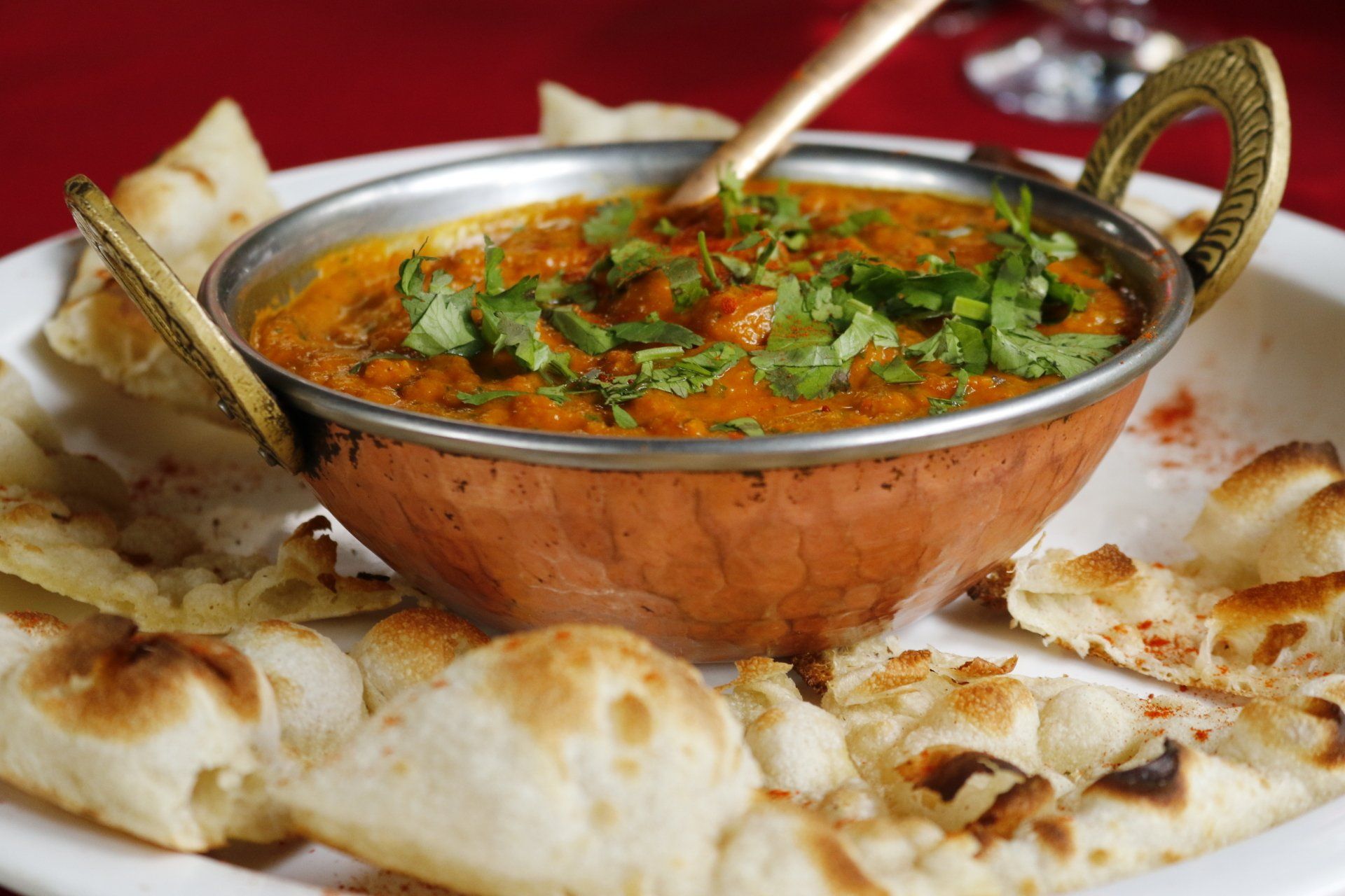 A bowl of curry is on a plate with bread.