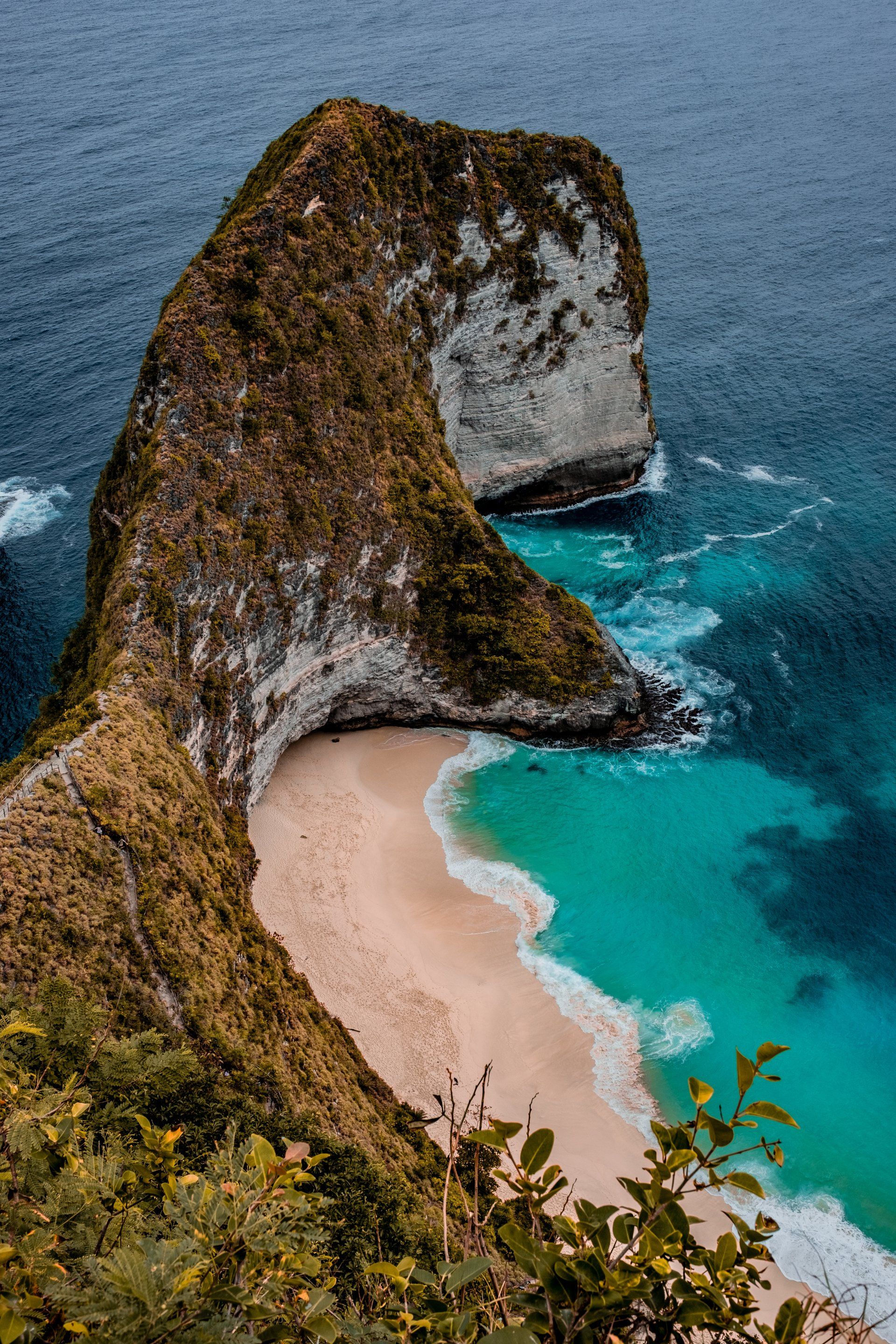 An aerial view of a cliff overlooking a beach in the ocean.