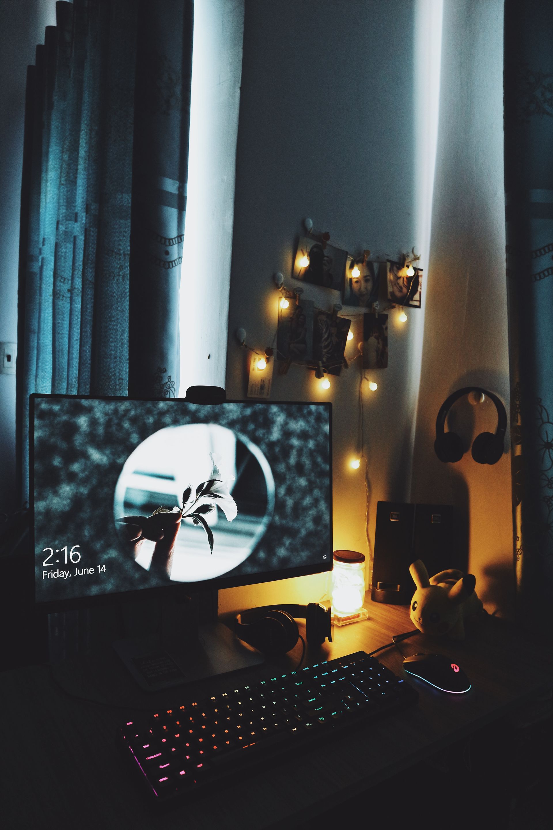 A computer monitor is sitting on a desk next to a keyboard and headphones.
