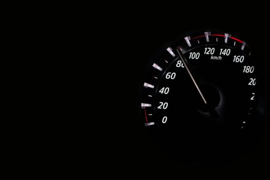 A close up of a speedometer on a black background.