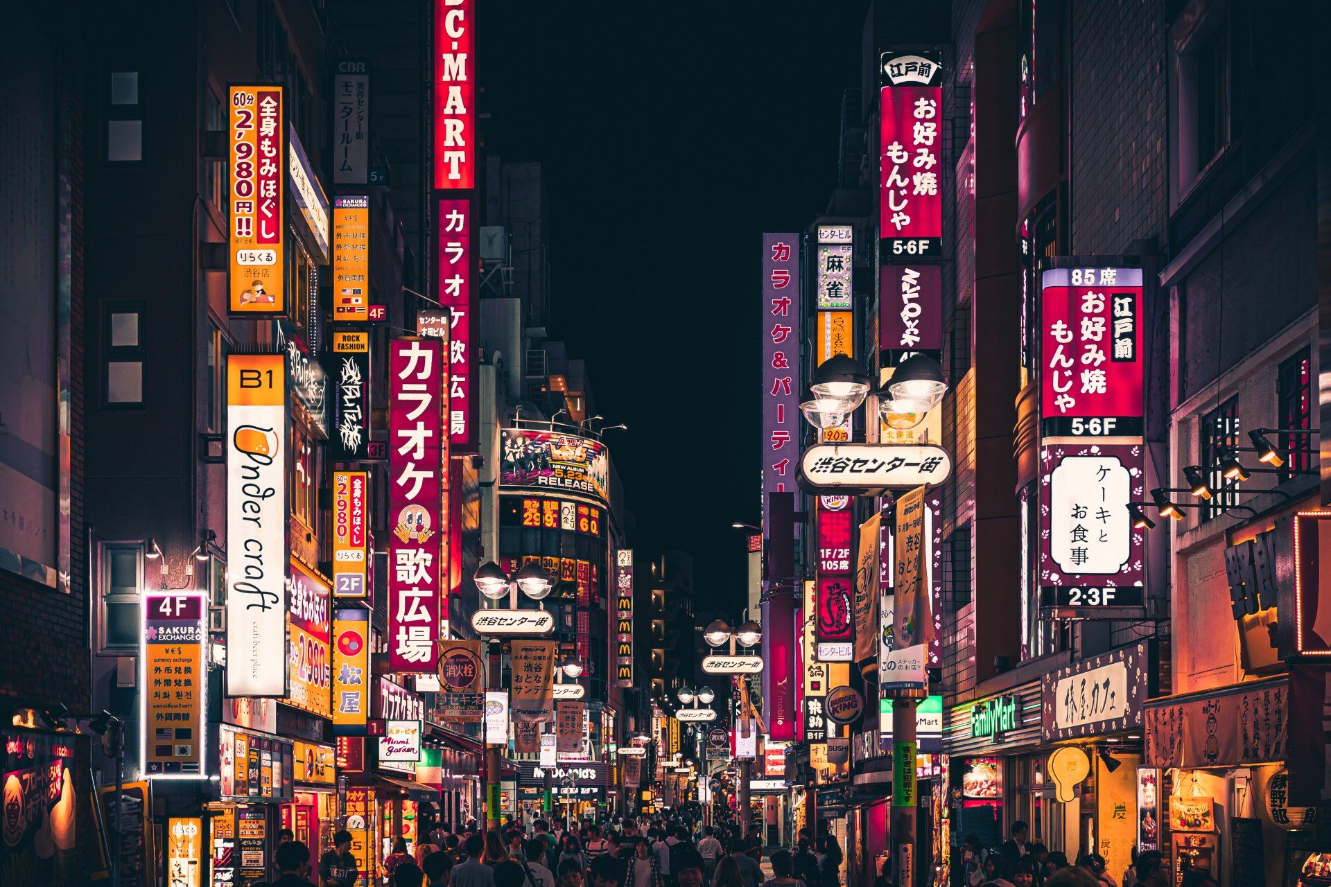 A crowd of people are walking down a busy street at night.