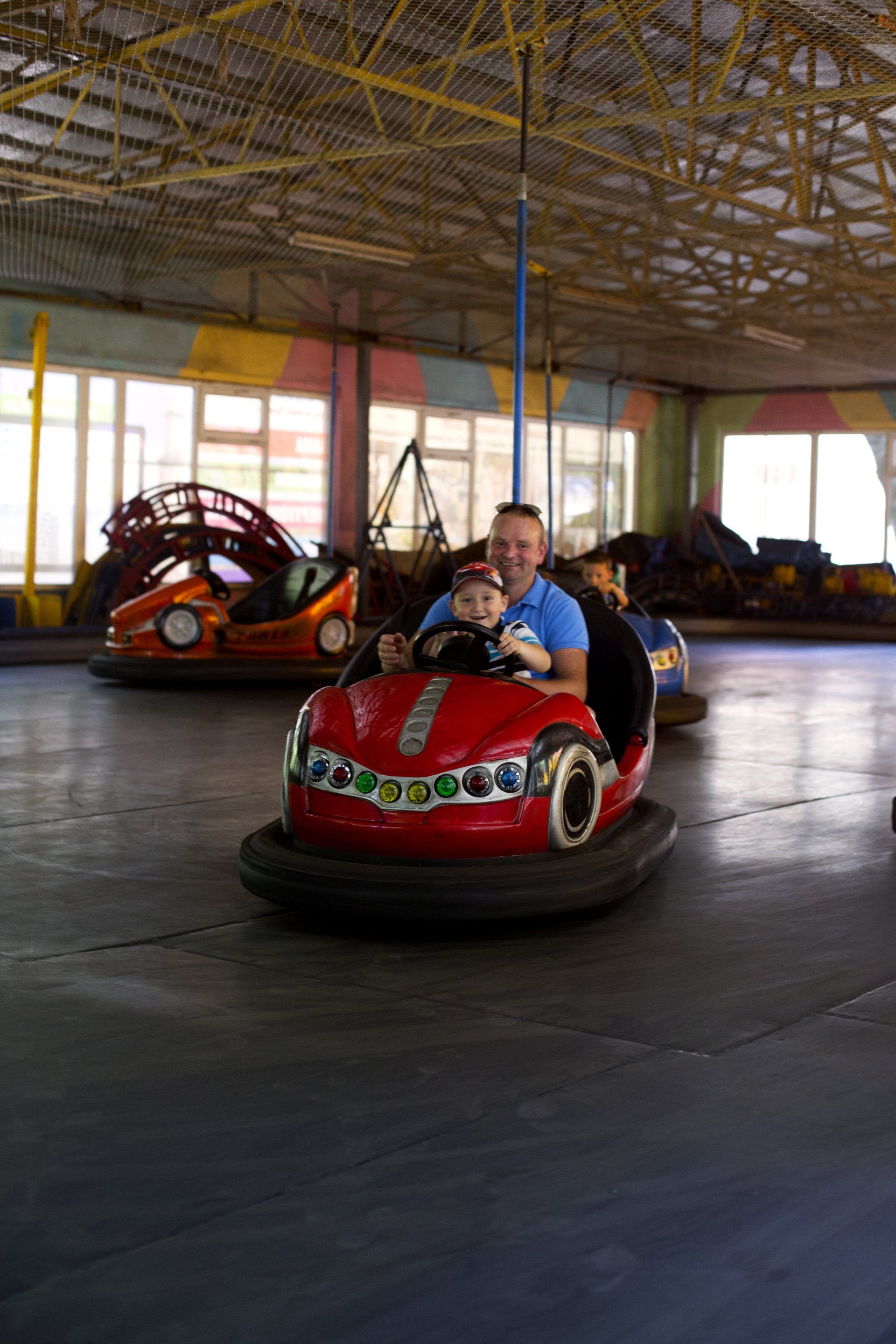 A man and a child are riding a bumper car at an amusement park.