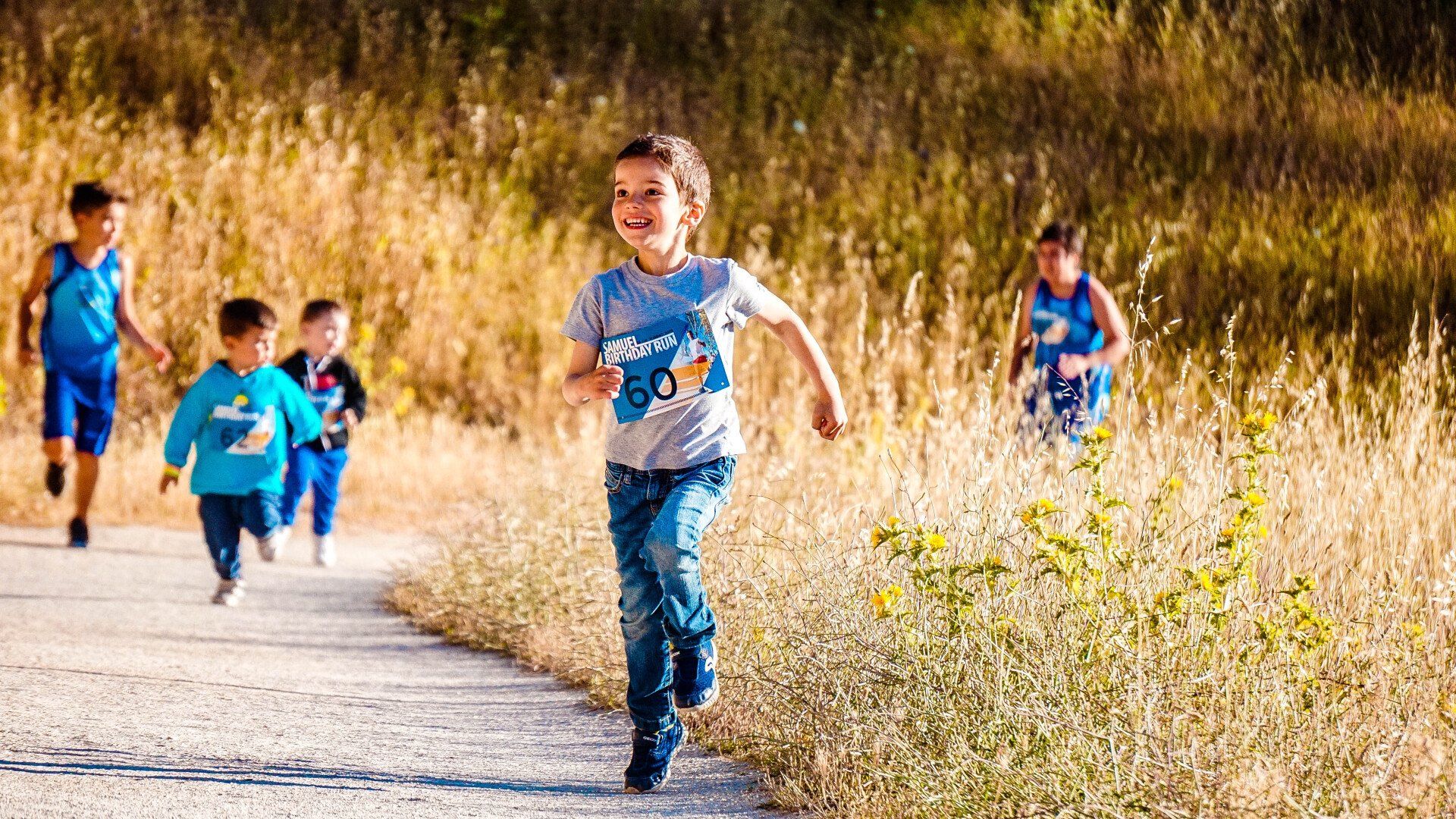 A group of young boys are running down a dirt path.