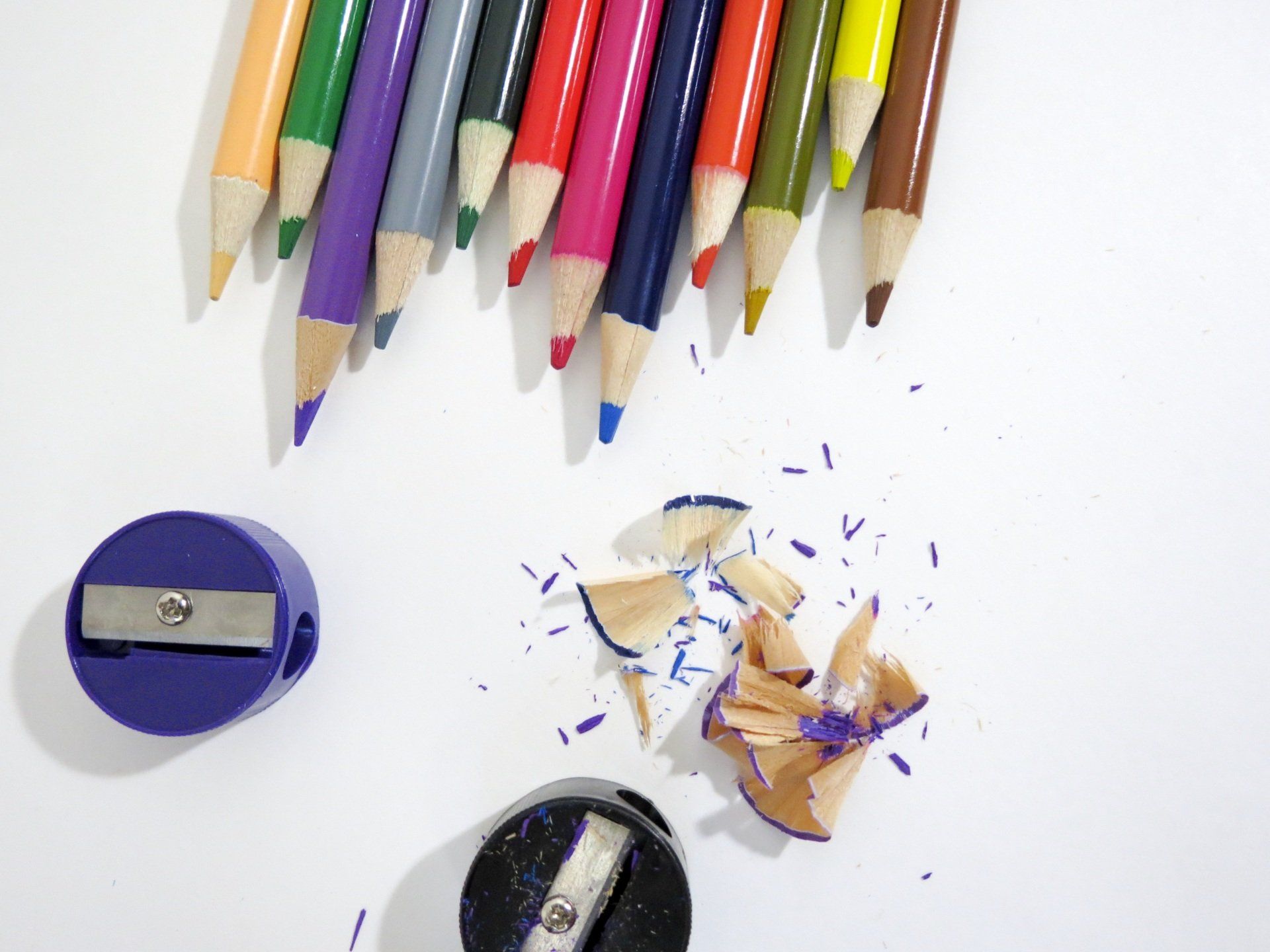 A group of colored pencils next to a purple pencil sharpener