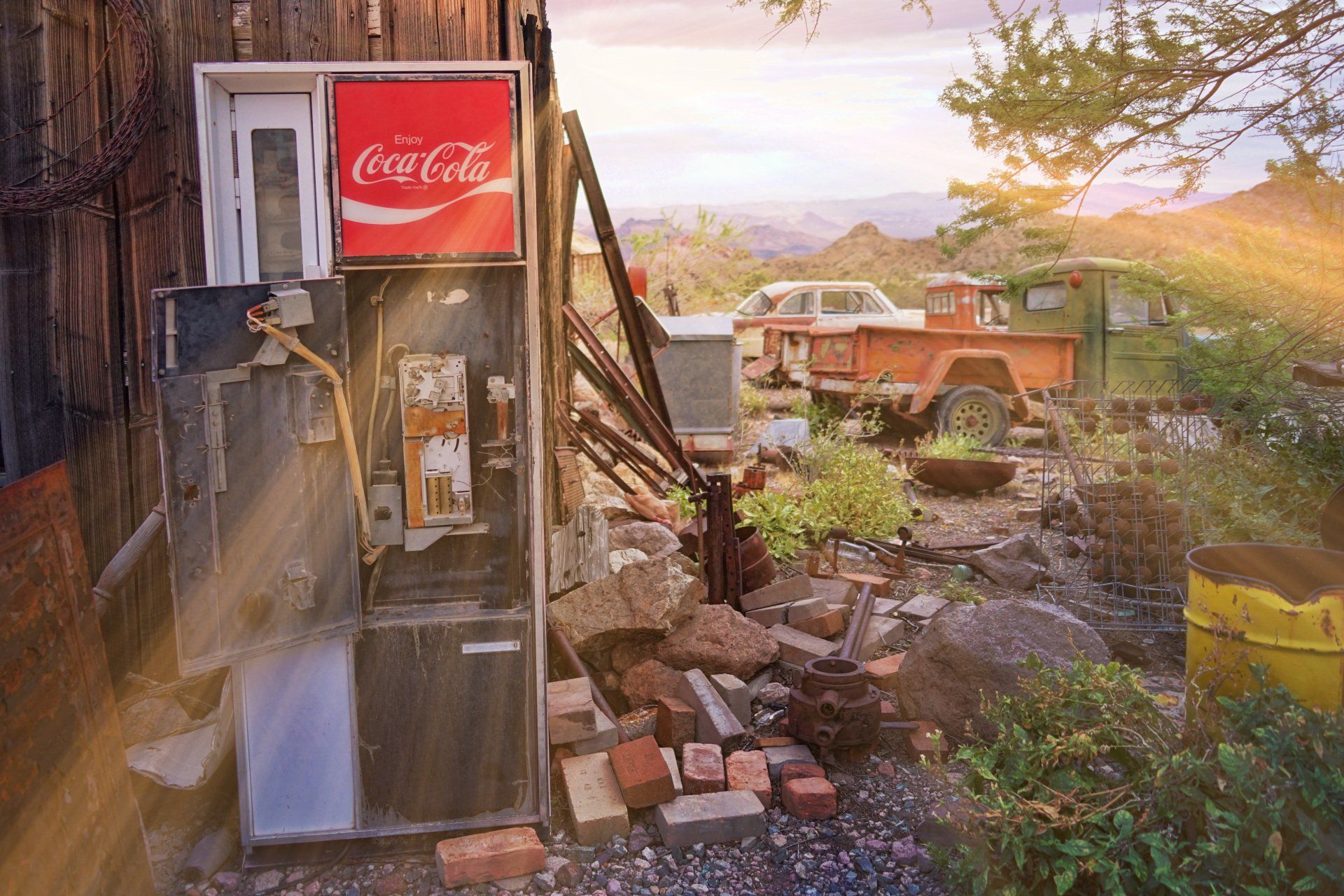 A coca cola vending machine is sitting in front of a wooden building.