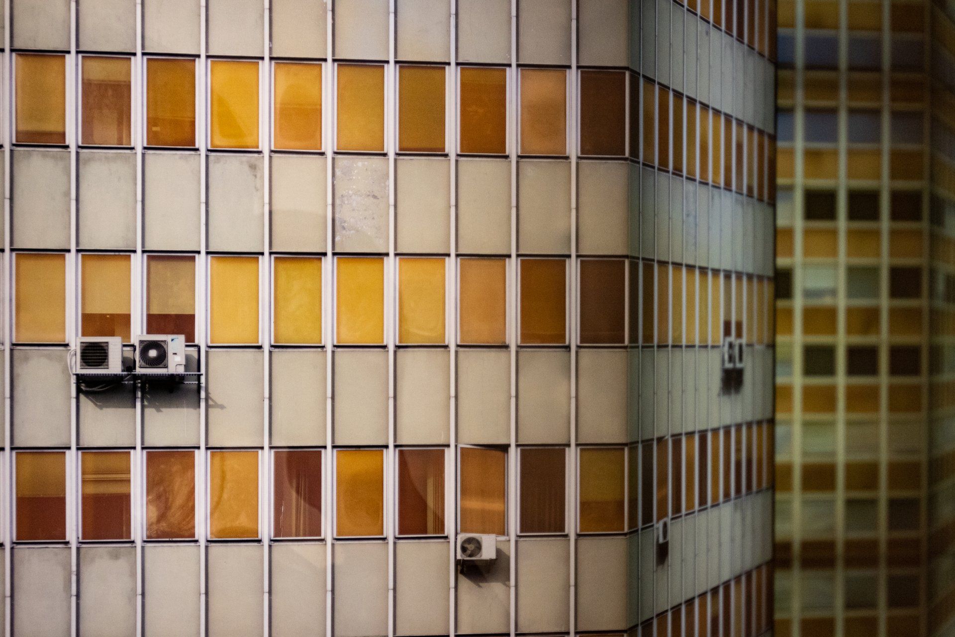 A building with a lot of windows and air conditioners on the side of it.