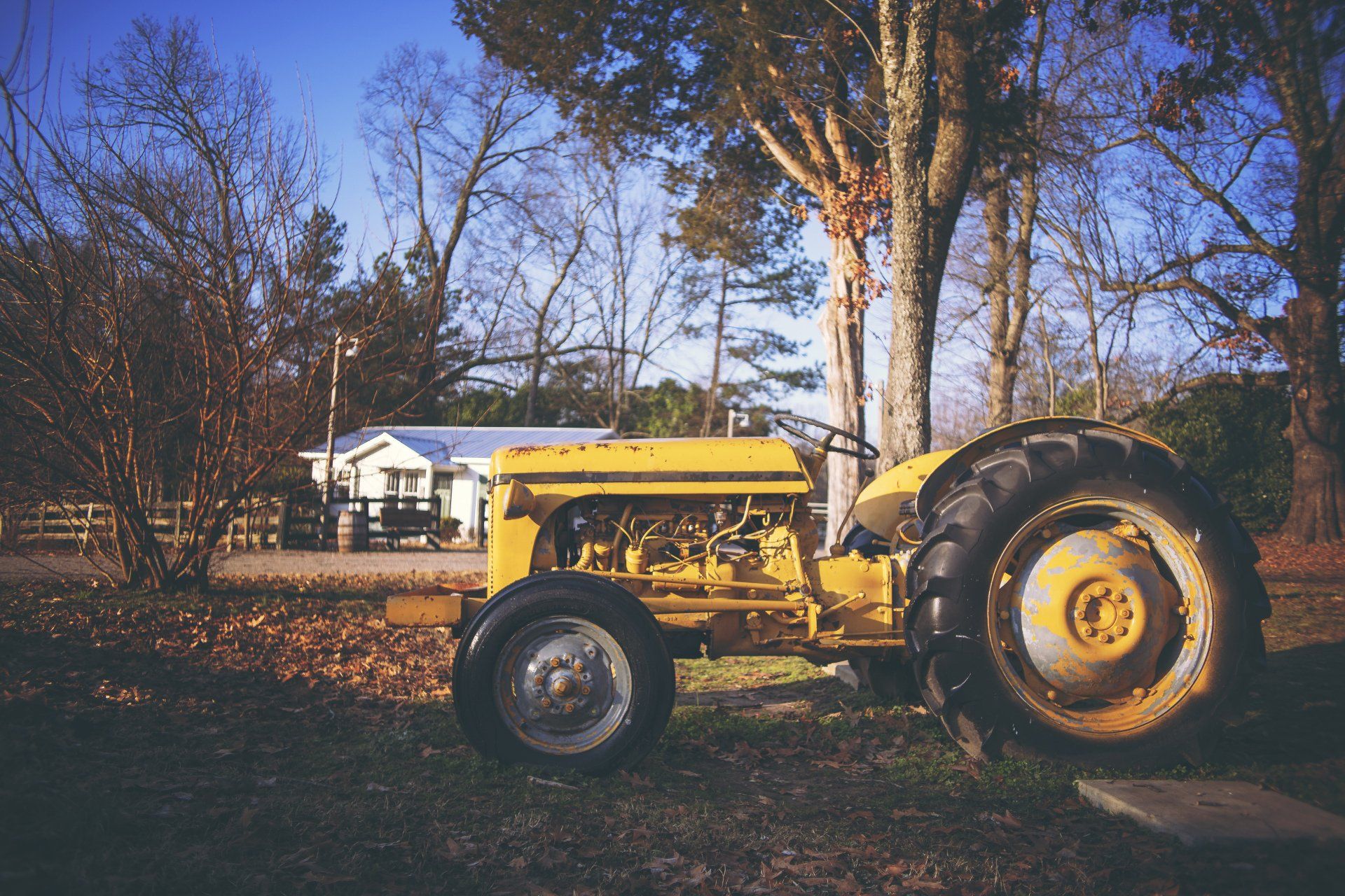 An old yellow tractor is parked in front of a house.