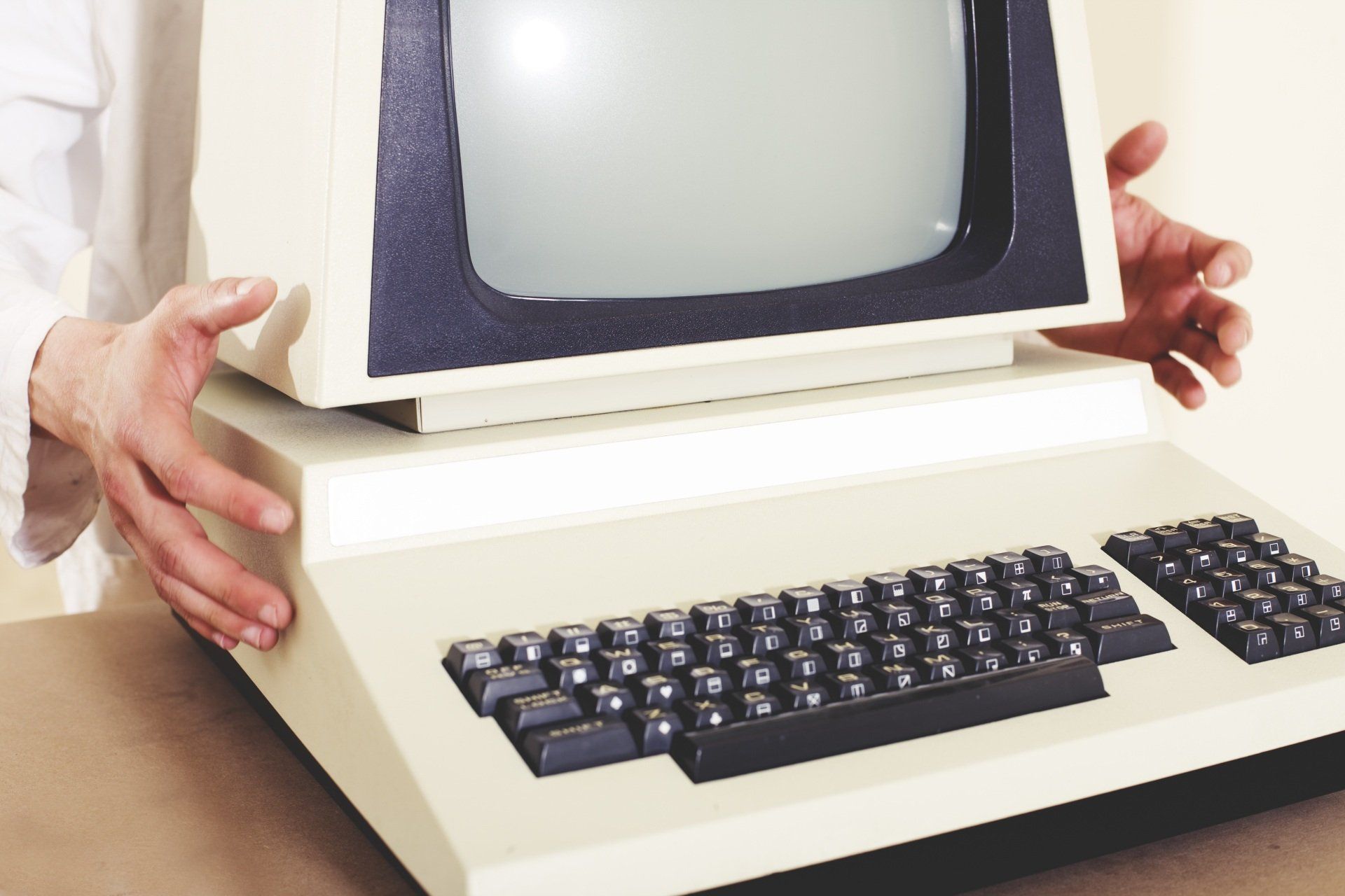 A person is holding an old computer with a keyboard