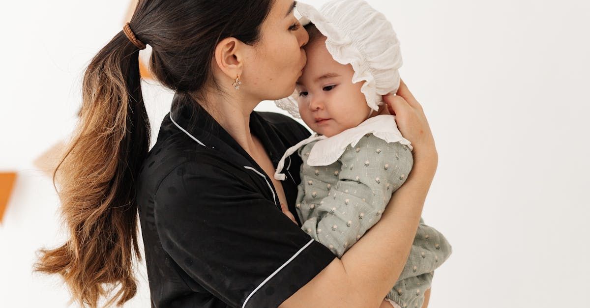 A woman is holding a baby in her arms and kissing it on the cheek.