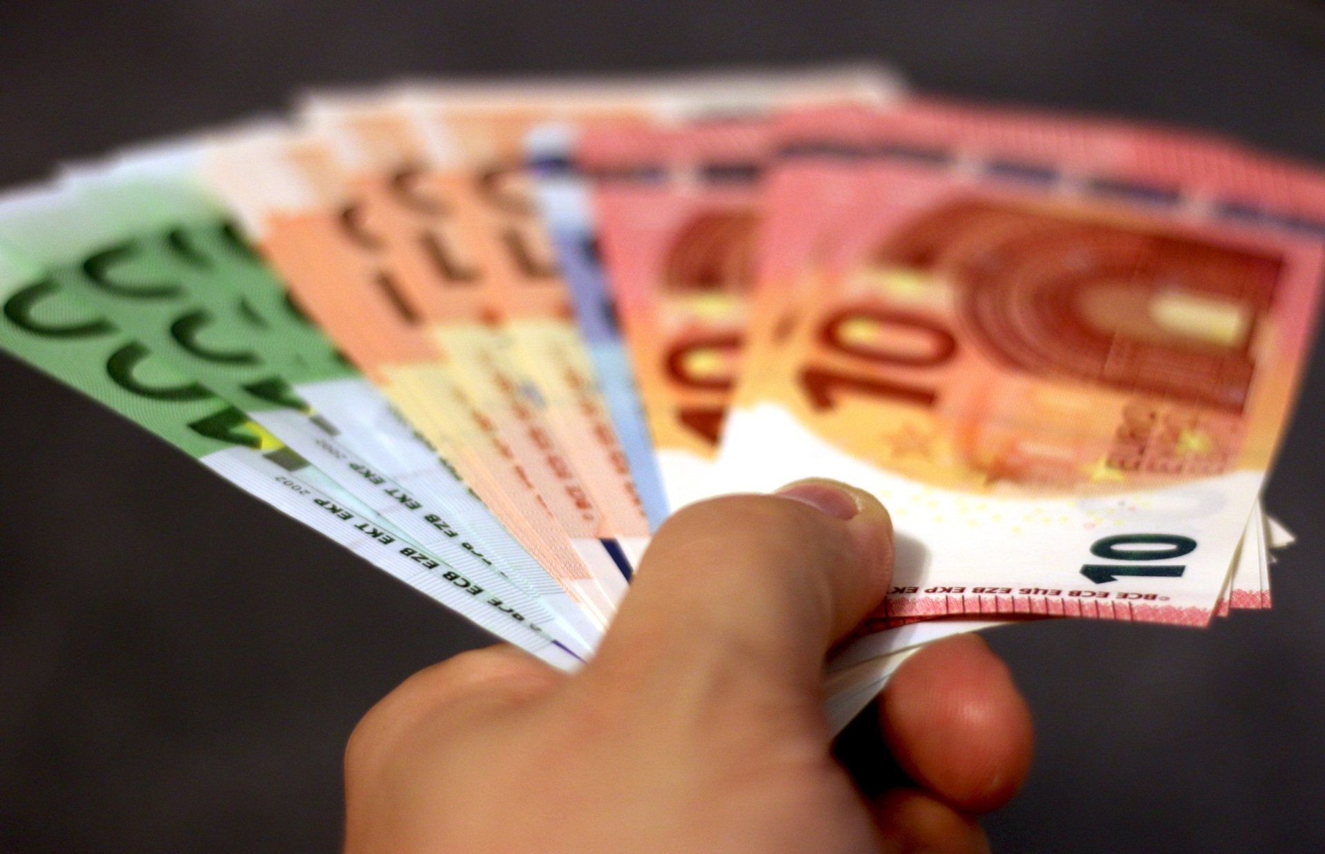 Una persona sostiene un abanico de billetes de euro en la mano