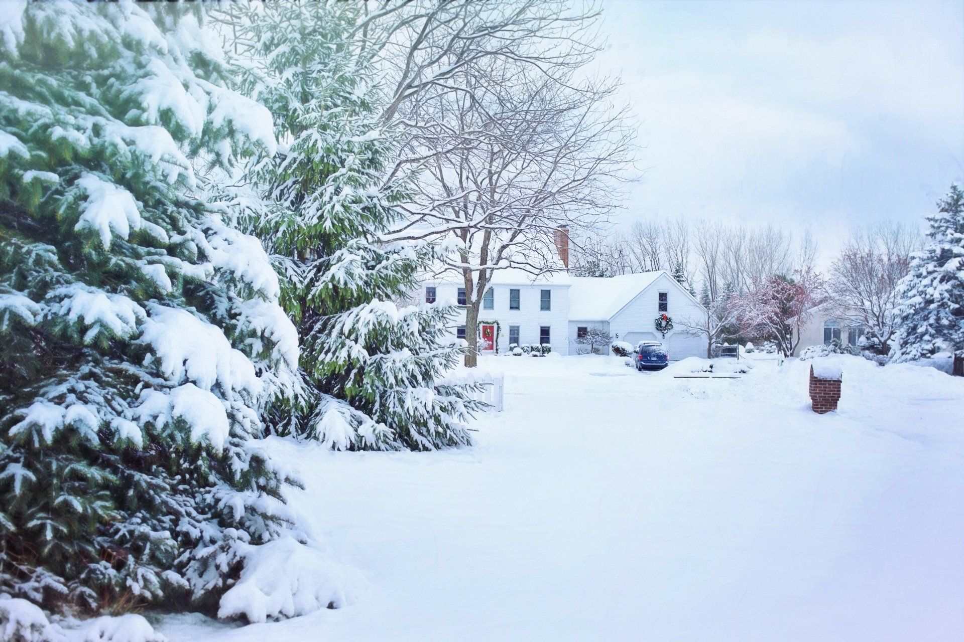 A white house in Vermont with the front yard covered in snow. 