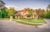 A large house is sitting on a lush green lawn in a residential neighborhood.