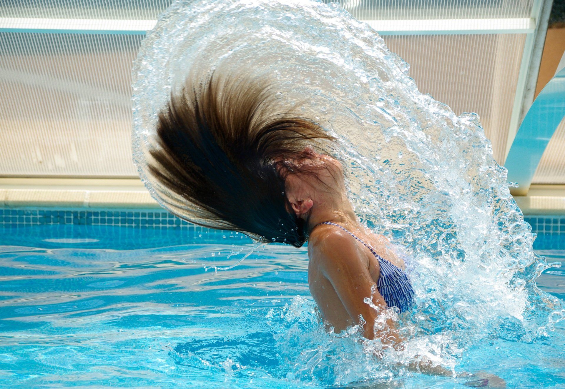 Una donna si sta spruzzando i capelli in una piscina.