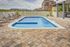 A large swimming pool surrounded by chairs and a fence.