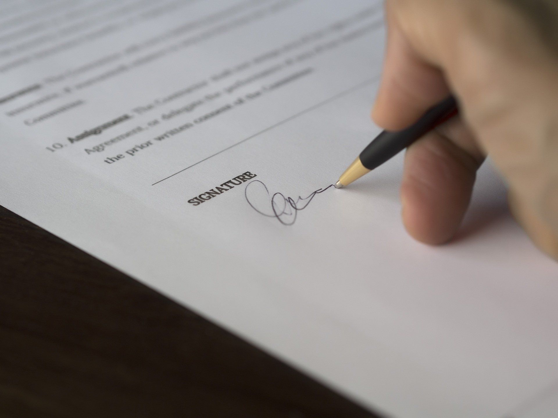 A person is signing a document with a pen.