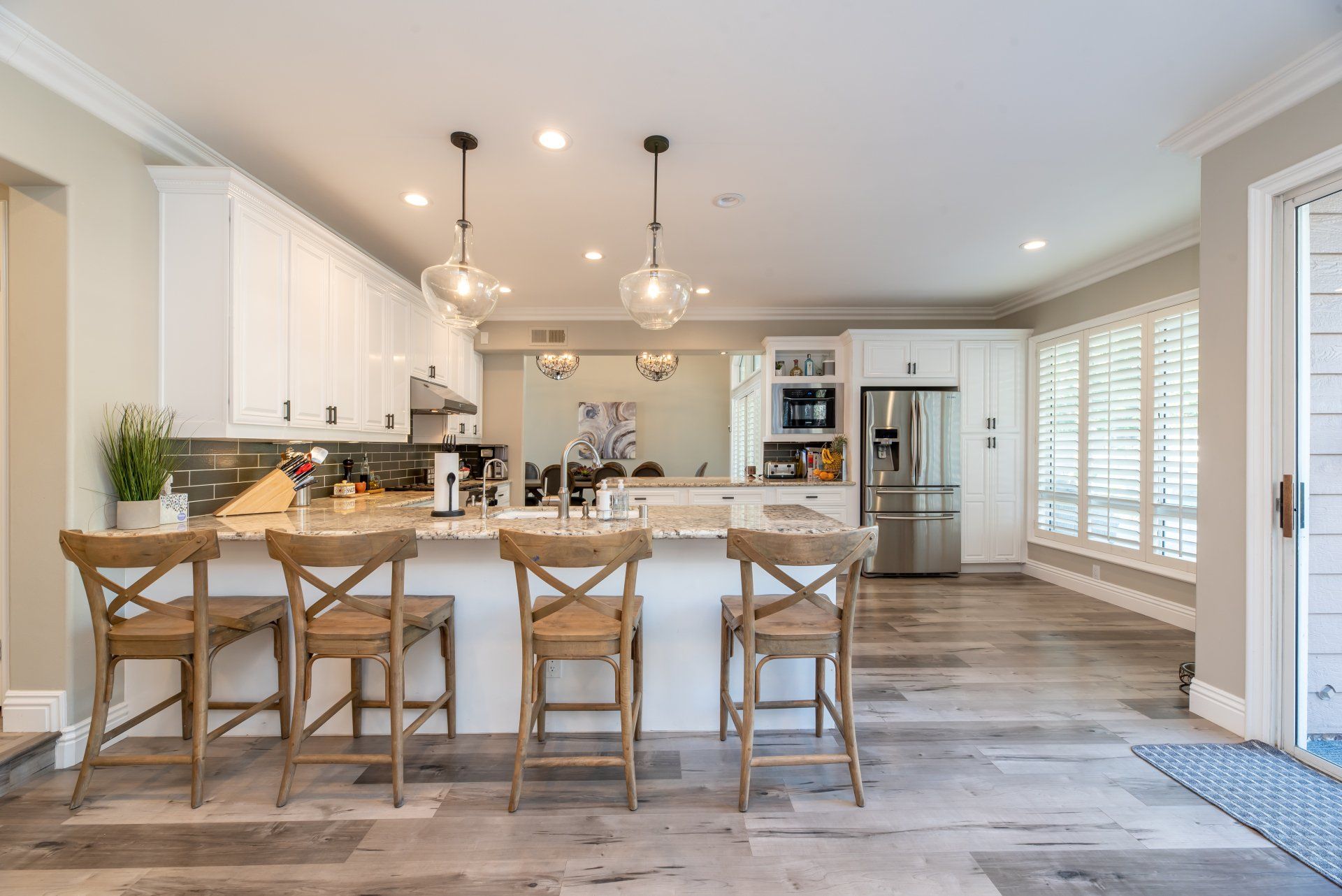 Kitchen with four chairs at the island and hanging lights.