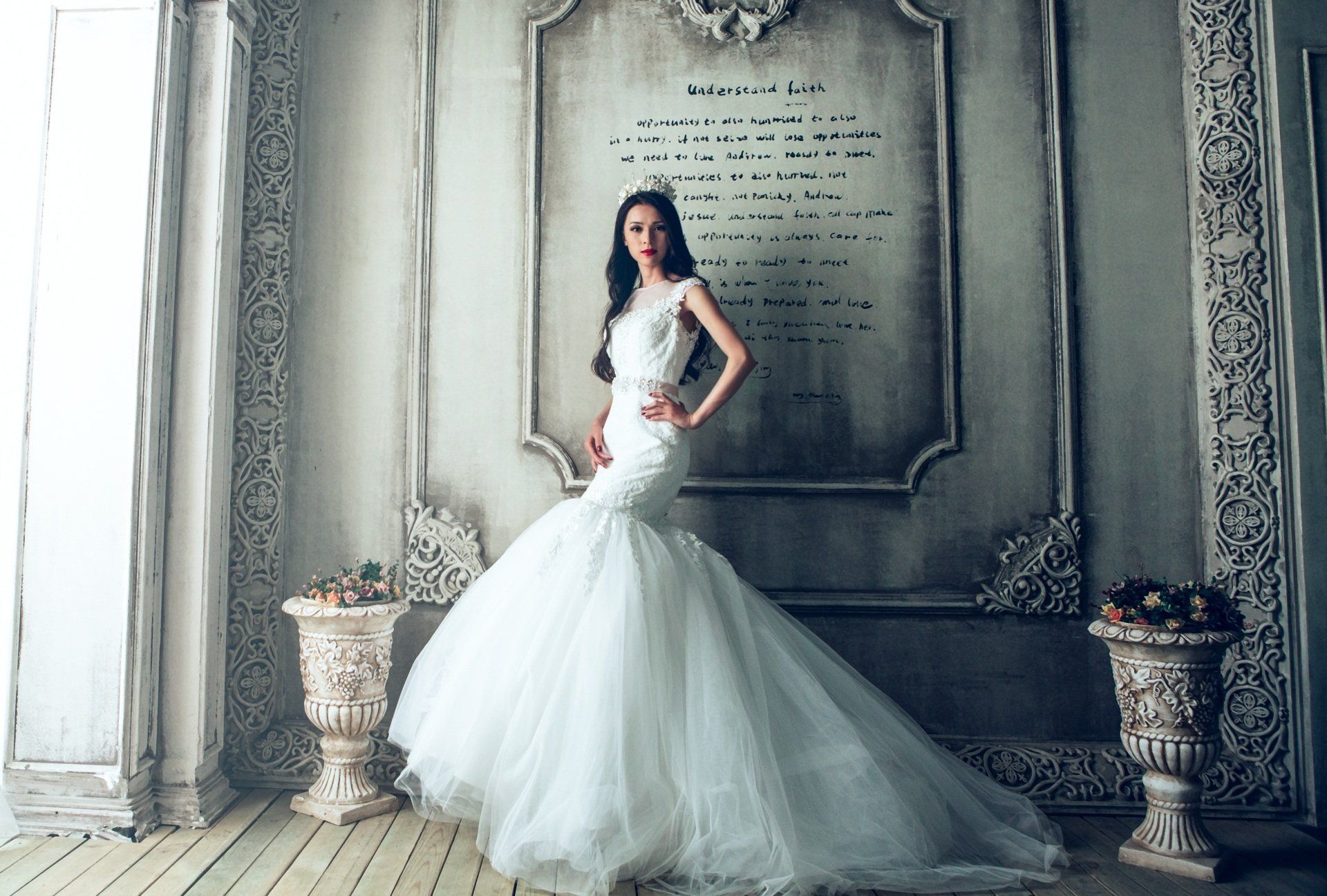 a woman in a wedding dress is standing in front of a wall